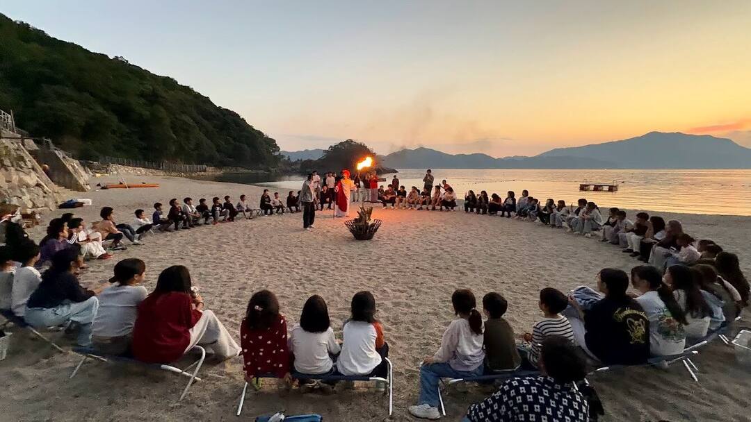 夕暮れの浜辺で輪になって座る参加者たち